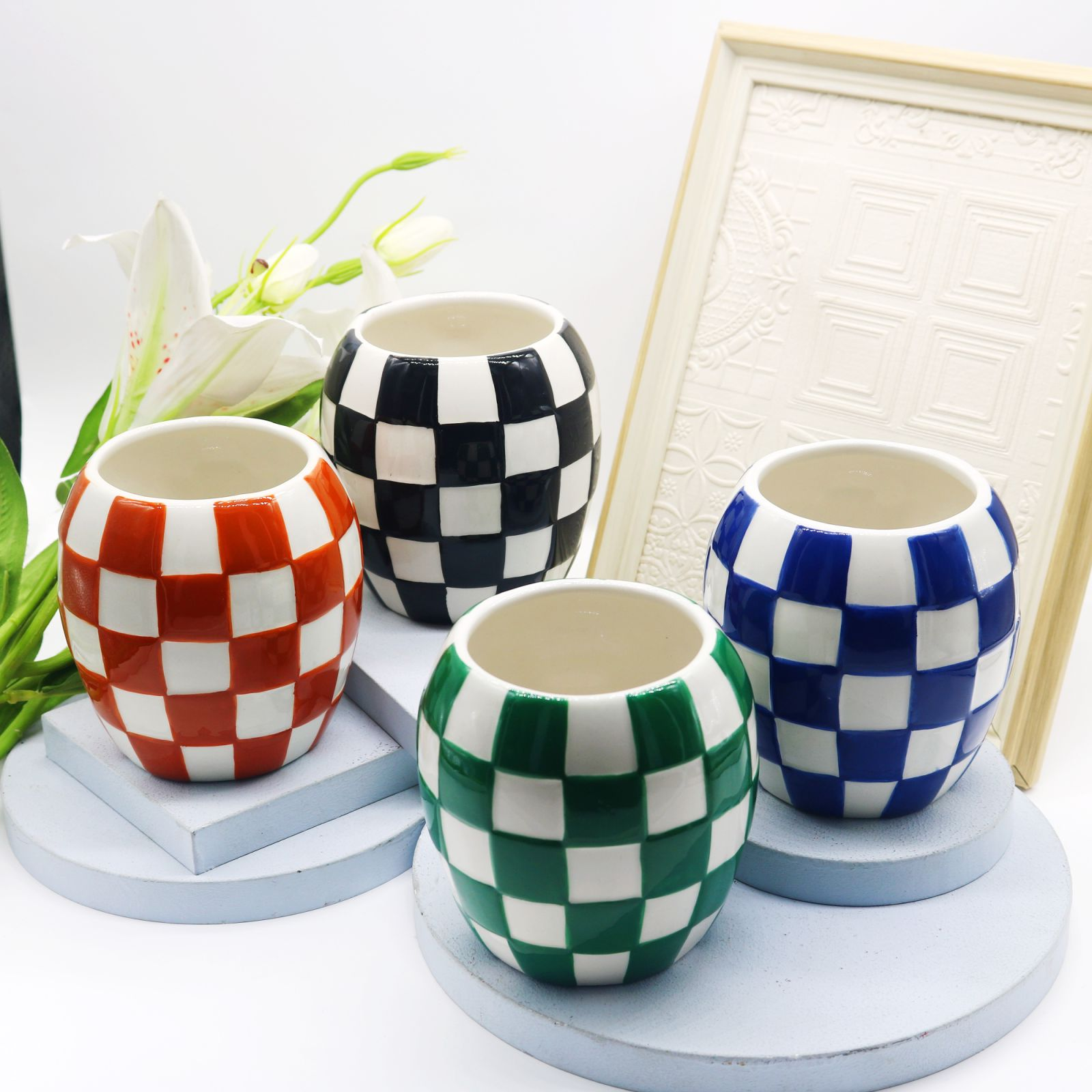 four checkered embossed ceramic candle vessels in red, black, green and blue.png