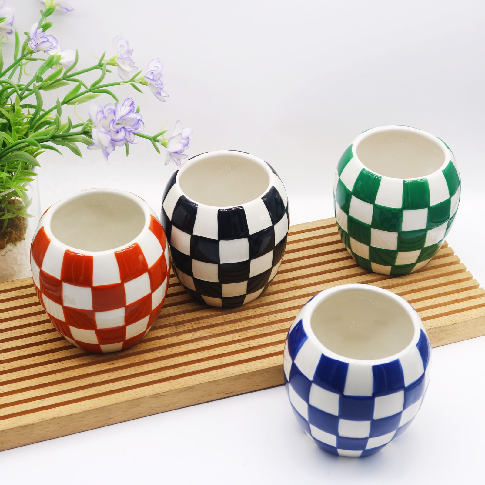 assorted checkered ceramic candle jars in red, black, green and blue on a bamboo tray - factory wholesale.png